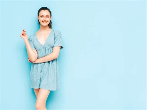 트렌디한 여름 파란색 드레스를 입은 젊은 아름다운 웃는 여성의 초상화 스튜디오에서 파란색 벽 근처에서 포즈를 취하는 섹시하고 평온한 여성 긍정적인 모델 재미 있고 미쳐가는