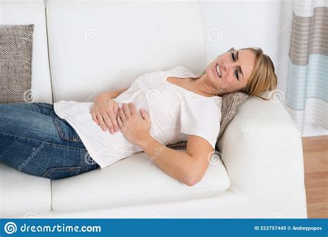 Woman Suffering From Stomach Pain While Lying On Sofa Royalty Free