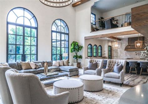 A Living Room Filled With Lots Of Furniture Next To Tall Windows And