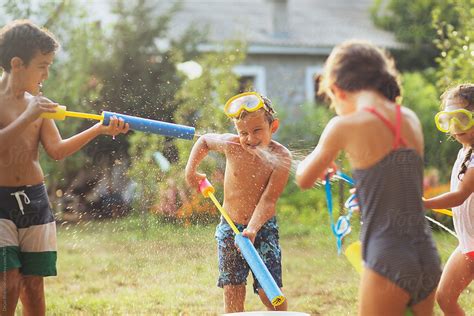 Children Playing With Water Guns In The Yard By Dejan Ristovski