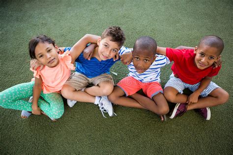 High Angle Portrait Of Happy Children Sitting On Grass Stock Image