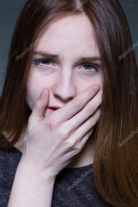 Портрет молодой напуганной и напуганной девушки смотрящей в камеру Закрывает рот рукой