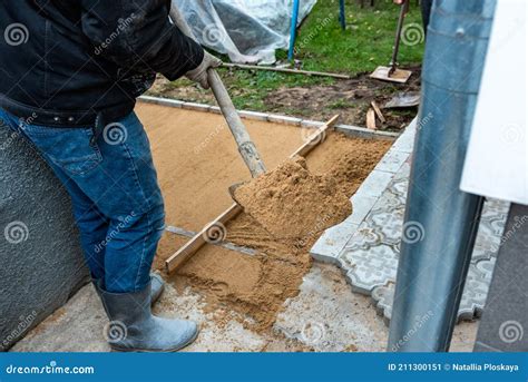 Worker Screeding Sand Bedding To Level For Laying Paving Slabs Stock