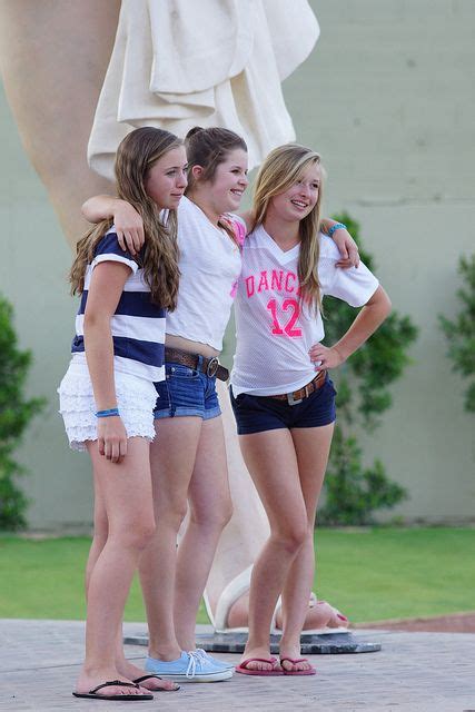 Three Girls Are Standing In Front Of A Statue