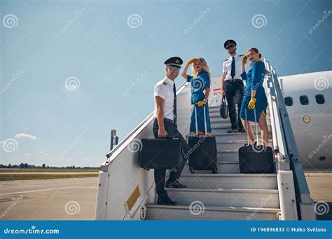 Beautiful Female Stewardesses With Two Handsome Pilots Looking And