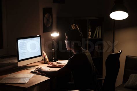 Focused Man Sitting And Using Computer In Dark Room Stock Image