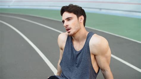 Close Up Of Tired Runner Sitting On Track After Running Workout