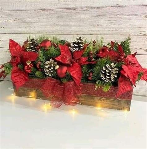 A Wooden Box Filled With Pine Cones And Red Poinsettis Sitting On Top