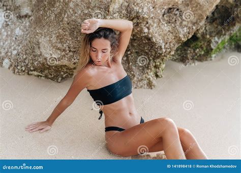 Sensual Tanned Girl In Black Swimsuit Posing Near Rock And Big Stone On