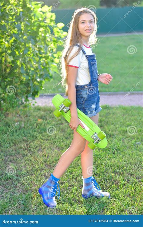 Красивый девочка подросток с скейтбордом в зеленом парке в лете Стоковое Фото изображение
