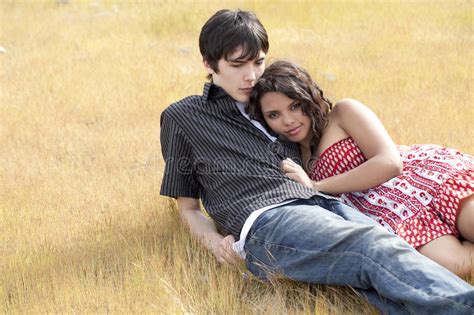 Young Teen Couple Reclining In Yellow Grass Stock Image