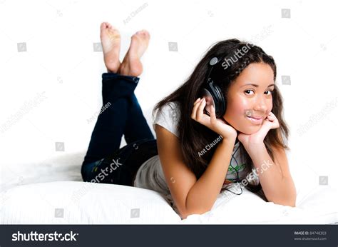 Pretty Teenage Girl With Headphones Lying Down Listening To Music With Legs Crossed Feet In The