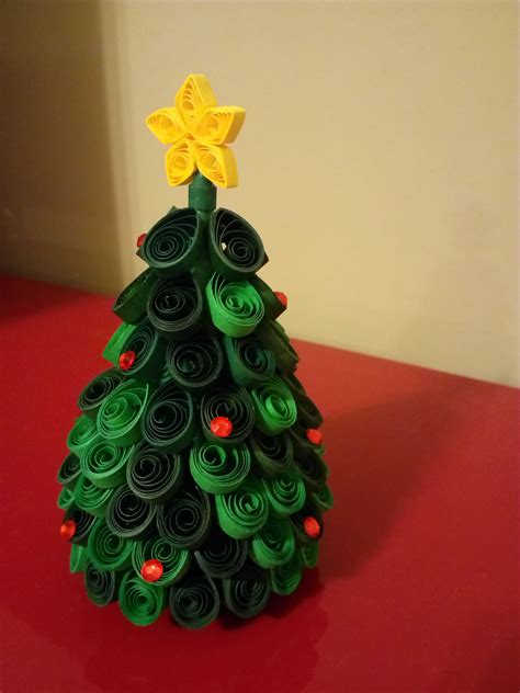 A Green Christmas Tree Made Out Of Rolled Up Paper On A Red Table Top