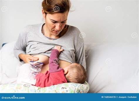 Mother Breastfeeding Her Newborn Baby While Pumping Milk From Her Other Breast To Store It In A
