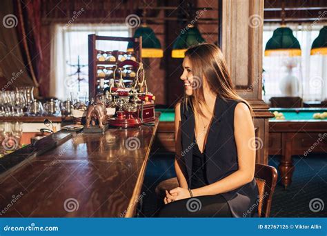 Beautiful Young Woman Sitting At The Bar Talking With The Bartender