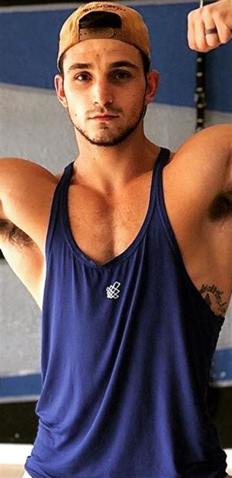 A Man In A Blue Tank Top Is Flexing His Muscles