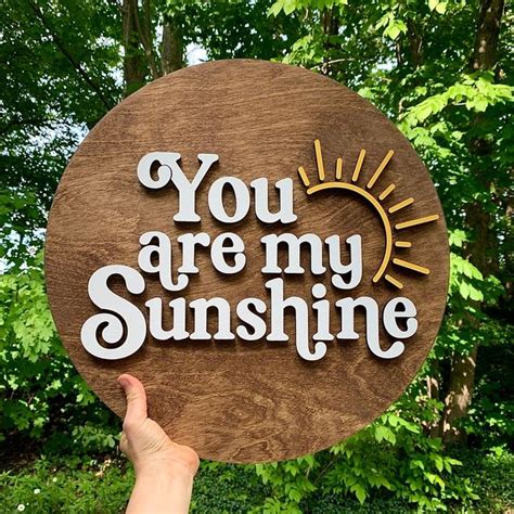 You Are My Sunshine Wooden Sign With Hand Painted Lettering In Front Of Some Trees