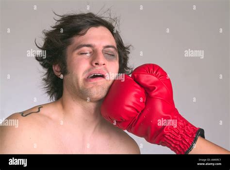 Male With Black Eye Being Punched In The Jaw With A Red Boxing Glove