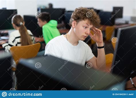 Focused Puzzled Teenage Boy Studying In Computer Lab Stock Photo