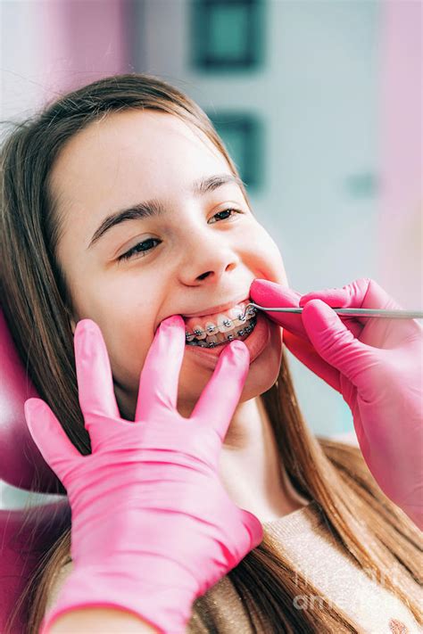 Orthodontist Fixing Girls Dental Braces Photograph By Microgen Images
