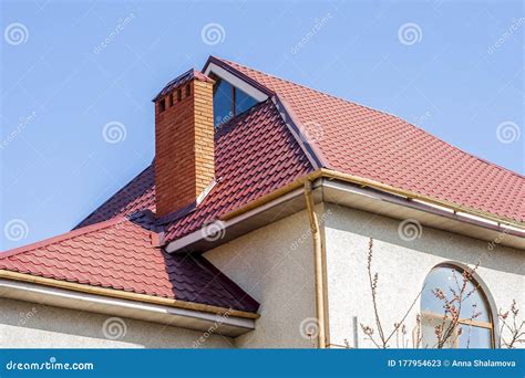 Red Tiled Roof Of The House With Windows On A Background Of Blue Sky