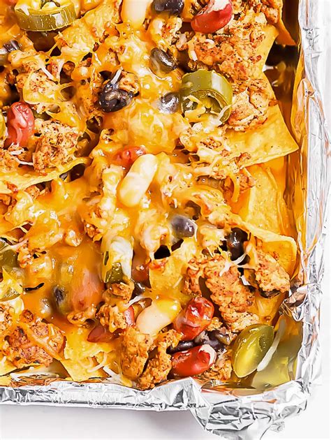 easy sheet pan chicken nachos made with crispy tortilla chips topped with seasoned ground chi