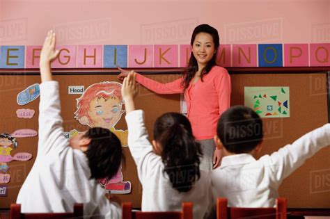 Teacher teaching alphabet with students raising hands in class - Stock ...