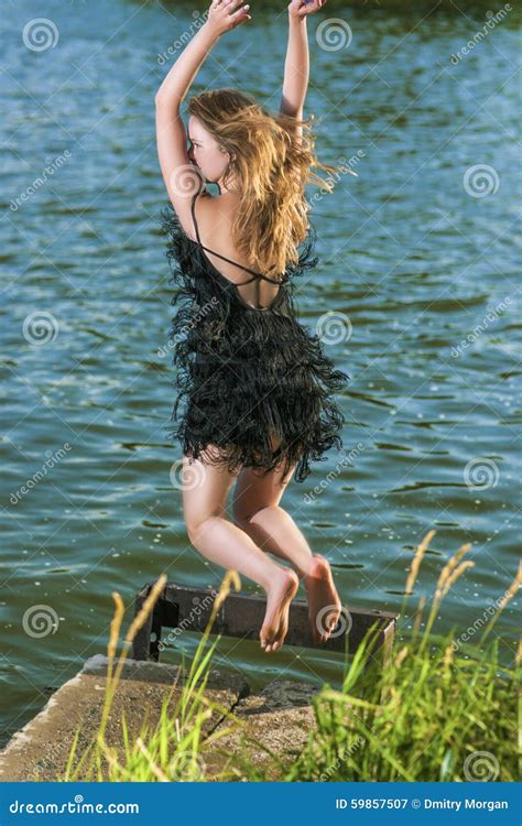 Caucasian Blond Woman In Sexy Dress Jumping Near Water Shore