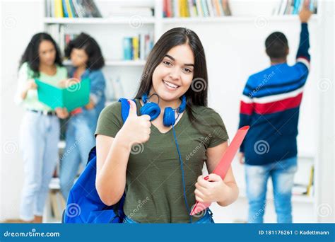 Young Spanish Female Student Showing Thumb Up With Group Of Students
