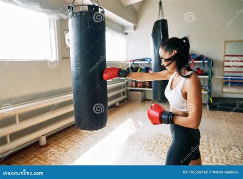 Female Boxer Hitting A Huge Punching Bag At Fitness Gym Stock Photo