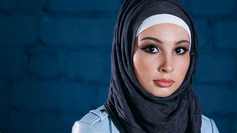 A Young Muslim Woman Dressed In Hijab Looks Straight Into The Camera