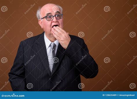 Overweight Senior Businessman Wearing Eyeglasses Against Brown B Stock