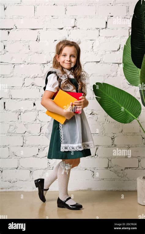 Full Length Portrait Adorable Little Schoolgirl In Uniform In Front Of White Brick Wall