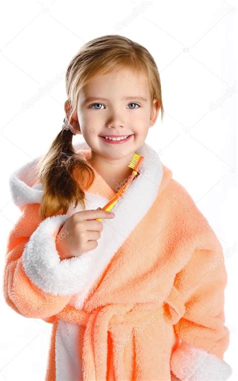Petite fille en robe de chambre se brossant les dents isolées image