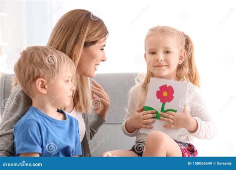 Mother Receiving Greeting Card From Her Cute Little Children At Home