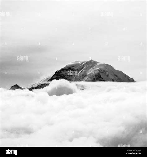 Snow Covered Mountain Peak Surrounded By Clouds Stock Photo Alamy