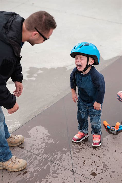 A Young Boy Cries To His Dad After Falling Off His Bike Into A Puddle