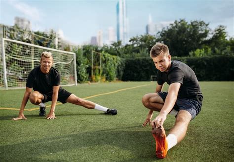 Premium Photo Two Male Soccer Players Doing Stretching Exercise On The Field Football