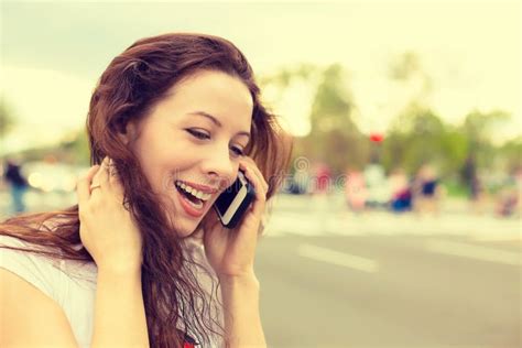 Jovem Mulher Feliz Que Fala No Telefone Celular Que Anda Em Uma Rua