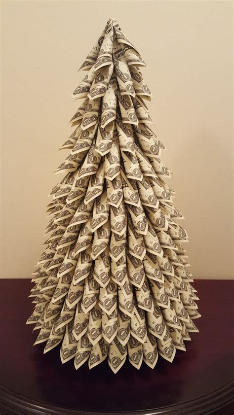 An Origami Christmas Tree Made Out Of One Hundred Dollar Bills On A Table