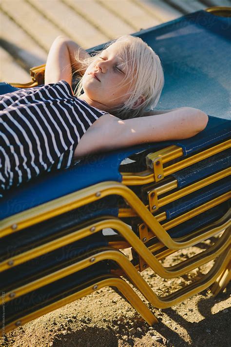 Little Blonde Girl Laying On The Top Of Piled Sunbeds By Stocksy Contributor Evgenij Yulkin