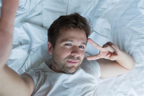 Premium Photo Handsome Man In White Shirt Taking A Selfie In Bed