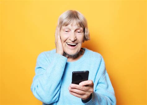 lifestyle tehnology and people concept old granny looks at her phone and is surprised stock