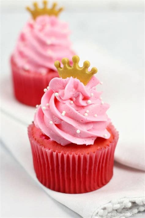 Two Cupcakes With Pink Frosting And A Gold Crown On Top Are Sitting On A Napkin