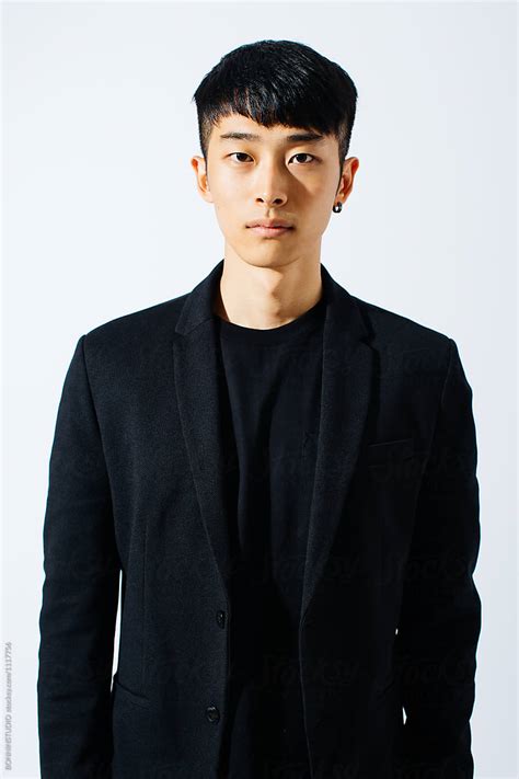 Portrait Of An Attractive Asian Man Wearing A Black Suit Over White
