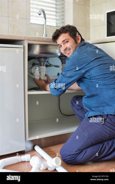 Plumber Working On Pipes Under Kitchen Sink Stock Photo Alamy