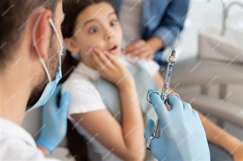 Premium Photo Portrait Of Scared Girl And Dentist Holding Syringe