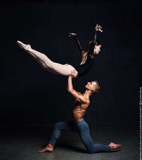 Two People Are Doing An Acrobatic Dance Pose In Front Of A Black Background