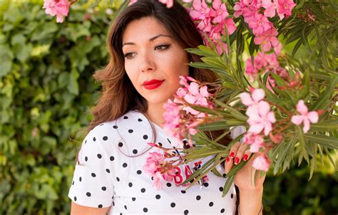 free photo woman in white and black polka dots dress near pink flowers during daylight
