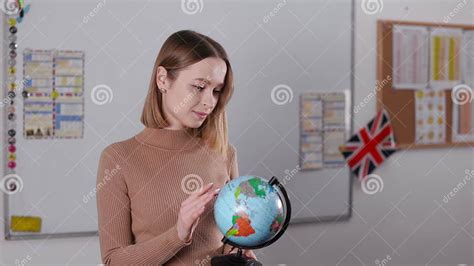 Tutor Holding And Rotating Terrestrial Globe In Classroom Stock Image